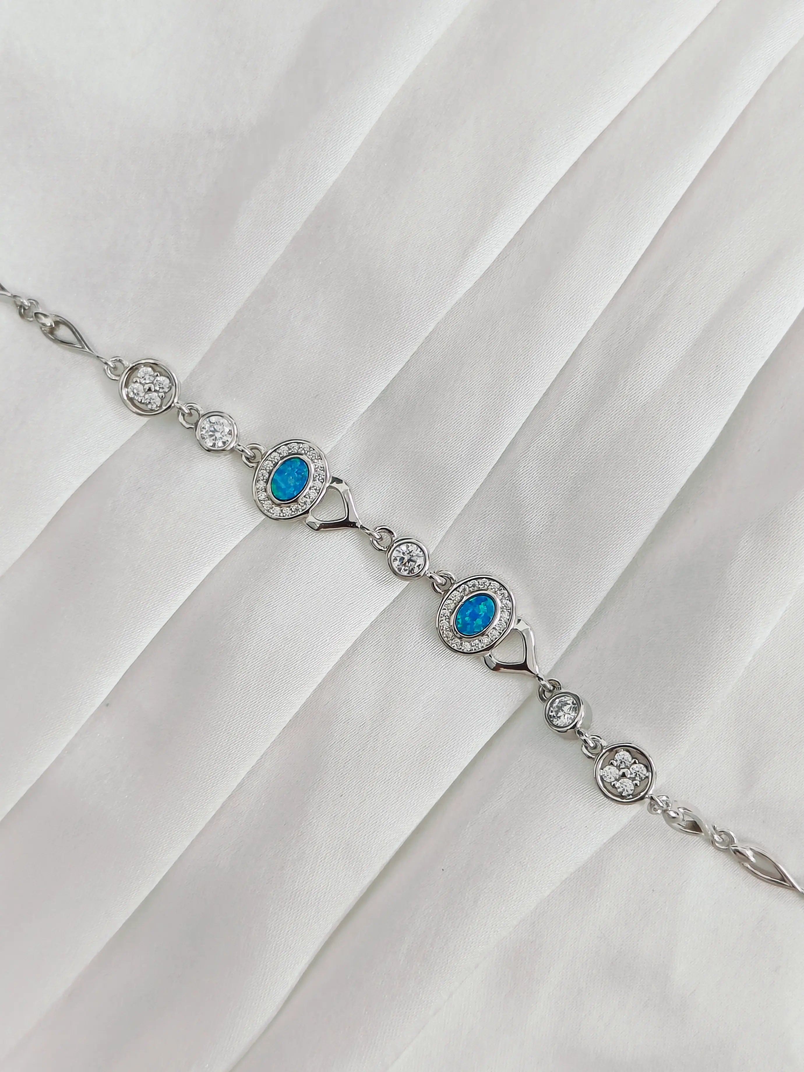 Silver bracelet with blue gemstones on a white fabric background